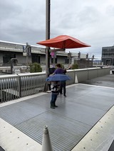 Child with Blue Umbrella on Modern Waterfront Plaza