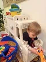 Toddler Playing with Toys in Baby Gate Enclosure