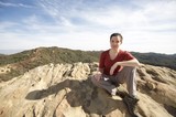 Hiker Rests Atop Rocky Summit with Mountain Vista