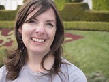 Joyful Woman Smiling in a Formal Garden Setting