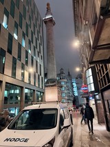 Monument Column Towers Over Modern London Street at Night