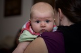 Wide-Eyed Baby Peering Over Parent's Shoulder