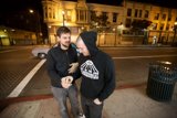 Two Men Standing on Sidewalk at Night