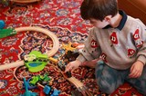Child Playing with Wooden Train Set on Persian Rug