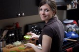 Smiling Woman Chopping Green Peppers in Kitchen