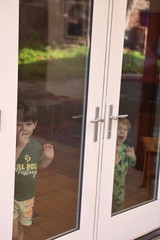 Two Young Boys Peering Through Glass Door