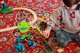 Child Playing with Wooden Train Set on Persian Rug