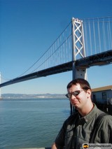 Man in Sunglasses standing in front of Suspension Bridge