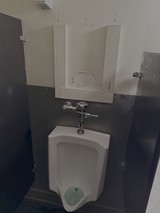 Damaged Bathroom with Vandalized Urinal