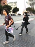 Two Men Walking Down a Street with a Skateboard