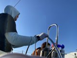 Waterside Worker Caption: A man in a hoodie tends to the hose on a boat while enjoying the blue skies and San Francisco Bay.