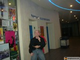 Man posing in front of a building with a sign