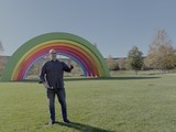 Man Poses Happily at Rainbow Art Installation