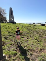 Child Exploring Near Modern Monument on Hillside