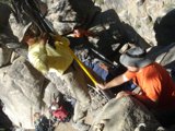 Man Scaling a Slate Rock while Holding a Yellow Pole