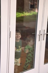 Two Young Brothers Looking Through Glass Door