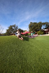Child Sliding Down Grassy Hill at Colorful Play Area