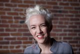 Joyful Woman in front of Brick Wall