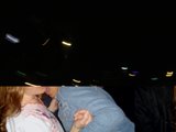 Dark Night Kiss Caption: A woman and man share a passionate kiss in a dimly lit room, with the night sky visible through the window behind them.