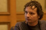 Curly Haired Man in Wooden Chair