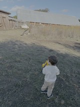 Child Playing with Yellow Toy in Rural Farm Setting