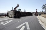 Crane lifting overturned truck on city street