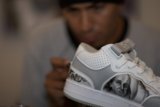 Man Holding Sneaker with Face on It