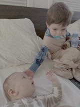 Big Brother Tenderly Watching Over Baby Sibling