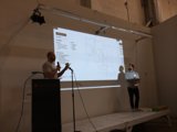 Two speakers presenting in front of a projection screen