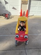 Toddler in Little Tikes Cozy Coupe with Traffic Cone Decoration