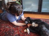 Woman Bonding with Black Dog Over Rawhide Treat
