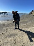 Man Standing on the Beach with a Piece of Wood