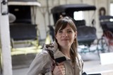 Woman Smiling Among Vintage Carriages in Museum