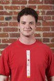 Red Shirted Teenage Boy Smiling in front of Brick Wall