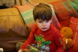 Young Boy Reading Christmas Book on Cozy Couch