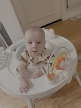 Baby in White Bouncy Seat with Toys