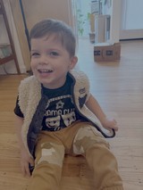 Happy Toddler in Sherpa Vest Playing at Home