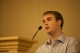 Blue Shirted Man Addresses Crowded Room