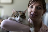 Woman Cradling Alert Tabby Cat Indoors