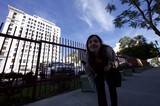 Woman Peering Through Iron Fence on City Sidewalk