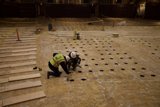 Two Workers Laying Plywood Flooring in Empty Room