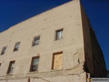 Abandoned Brick Building with Boarded Windows against Blue Sky