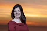Woman Smiling Radiantly Against Golden Sunset Sky