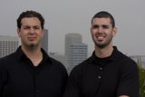 Two Men Smiling in Front of a Skyscraper
