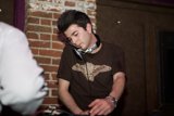 DJ Brownshirt brings the beats Caption: A man in a brown shirt shows off his DJ skills at Respect SF in 2007, surrounded by electronic equipment and brick walls.