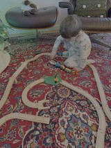 Toddler Playing with Wooden Train Set at Home