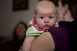 Wide-Eyed Baby Resting on Mother's Shoulder