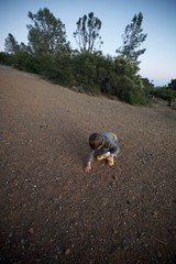Young Explorer Discovers Wonders in Gravel at Dusk