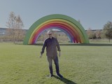 Person Standing Before Colorful Rainbow Art Installation