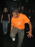 Orange Shirt Man at the Sunday Club Caption: This man in an orange shirt is ready to dance the night away at the Sunday Club with his jeans and shoes.